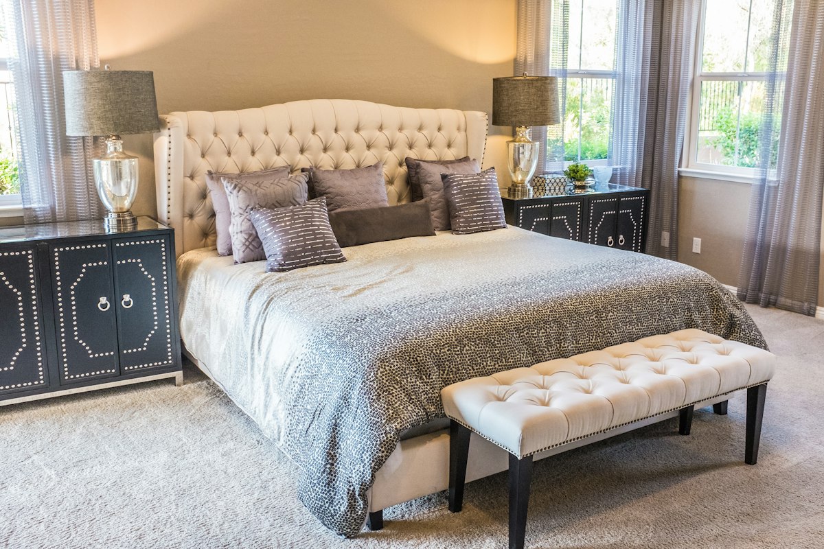 Neutral bedroom with upholstered bed, patterned bedding and bedside lamps