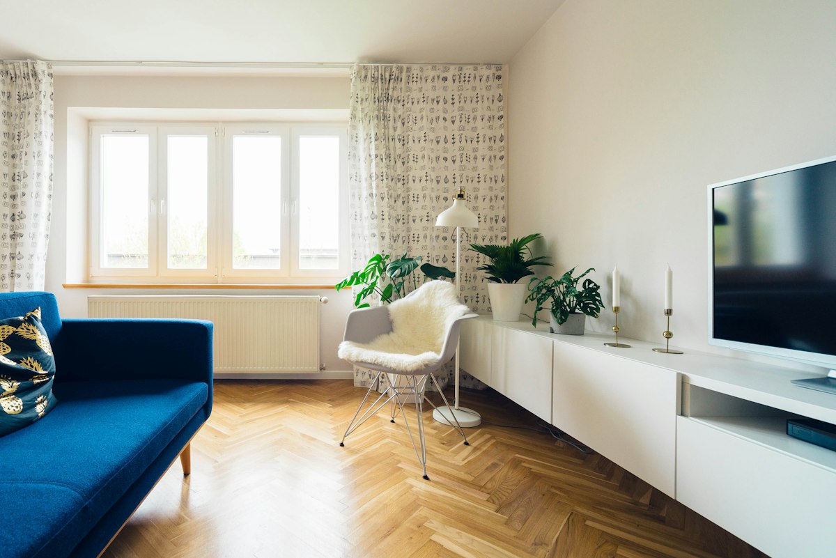 Compact living room with a blue sofa, white media storage and a chair beside the window